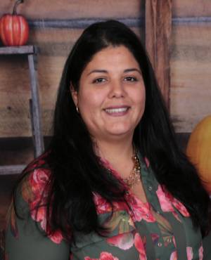 A woman in floral shirt smiling for the camera.