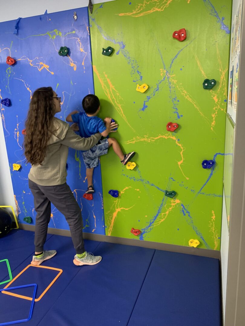A woman and child are climbing on the wall.